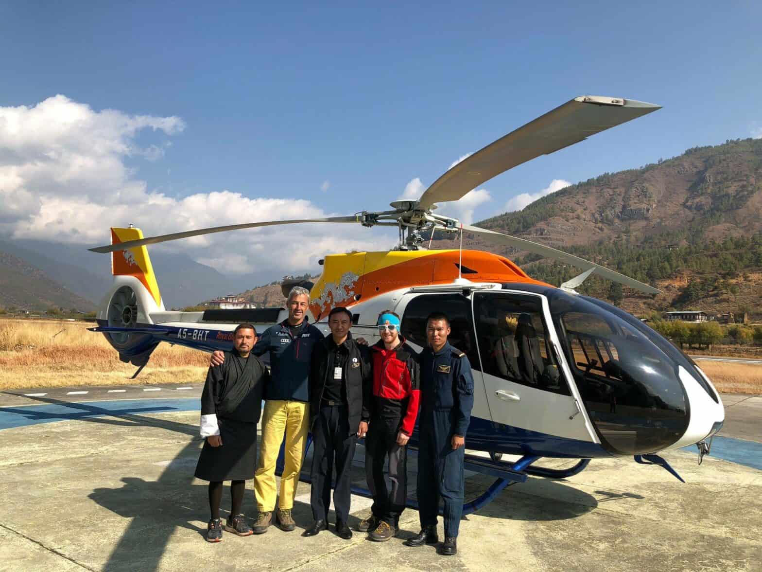 Sie sehen Dr. Jakob Ebner vor einem Helikopter der als Ehrenamtliche Tätigkeit, für die Bergrettung eine Reise nach Bhutan unternommen hat.